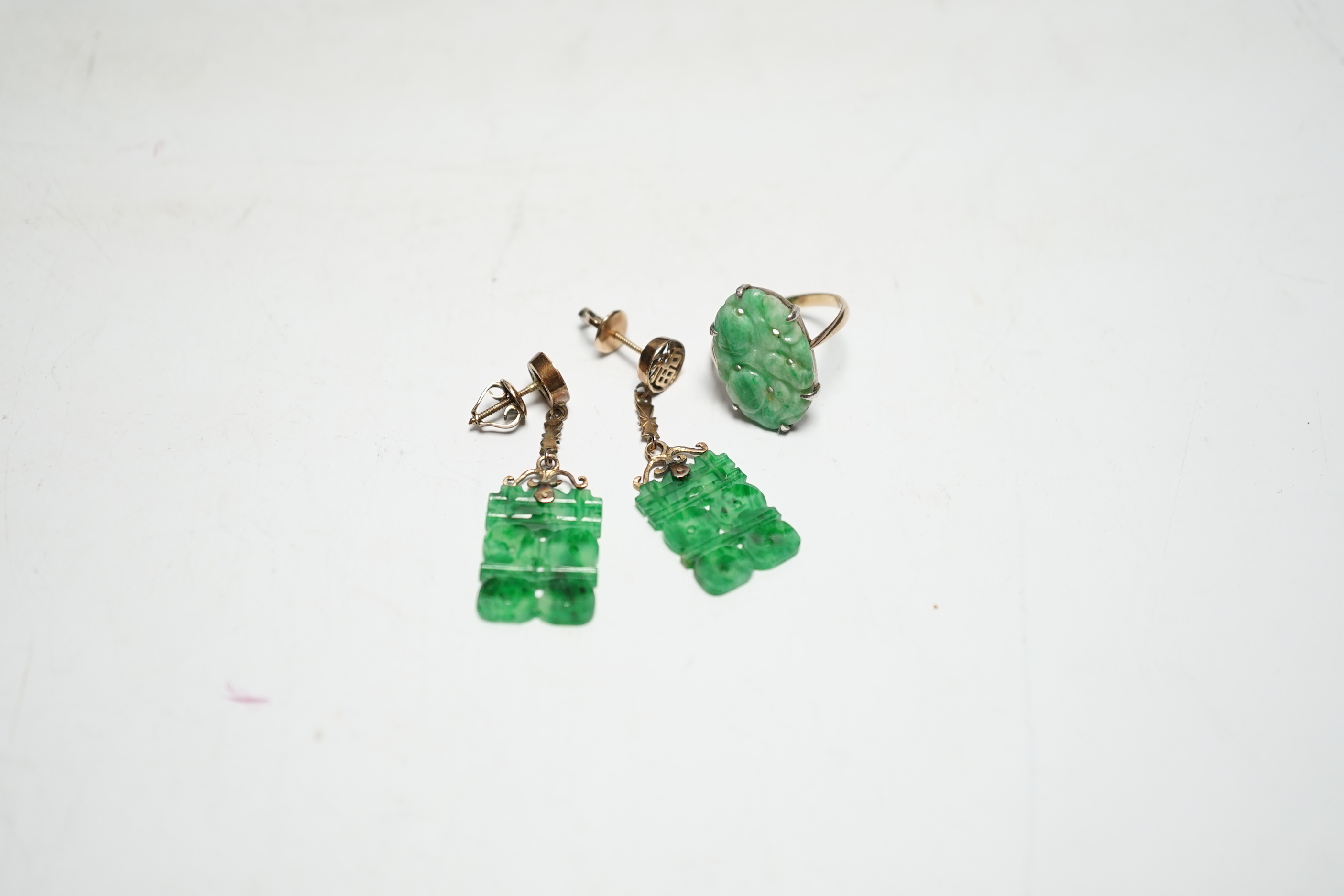 A pair of Chinese 14k yellow metal and jade set drop earrings, 37mm and a yellow metal and carved oval jade set ring, gross weight 6.1 grams.